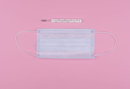 Disposable medical blue mask, personal protective equipment with mercury thermometer temperature on pink backgraundの写真素材