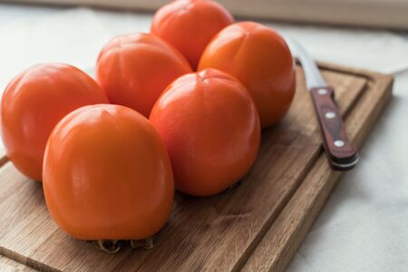 fresh ripe persimmon fruits, winter fruit, cut on board and black backgroundの写真素材