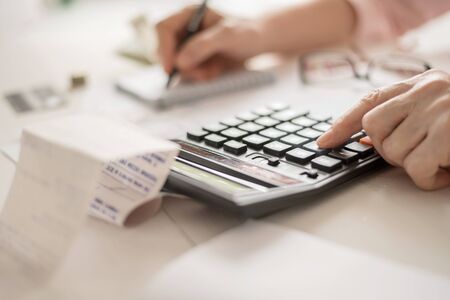 Pension calculation concept, old hands counting finances on a home calculator ,の写真素材