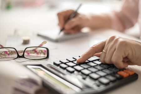 Pension calculation concept, old hands counting finances on a home calculator ,の写真素材