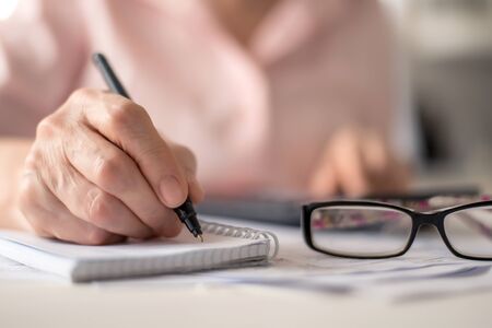 Pension calculation concept, old hands counting finances on a home calculator , close- upの写真素材