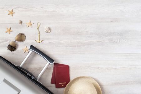 Travel preparation. Glasses, passports, hat and suitcase top view on a wooden background. Packing the suitcase.の写真素材