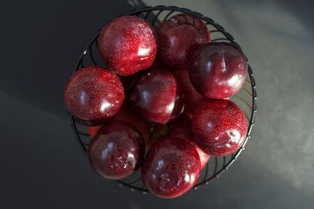 fresh round purple plums, in a black fruit bowl, on a black background. closelyの写真素材