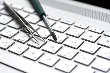 Laptop repair, screwdrivers close-up on a gray keyboard. Computer service macroの写真素材