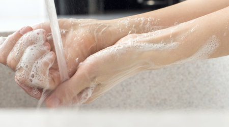 Washing of hands with soap under the crane with water.