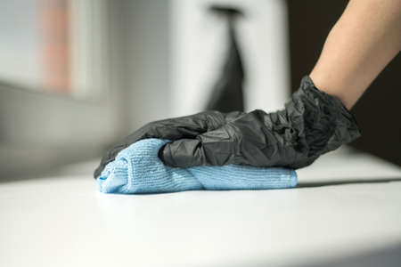 A hand in black gloves holds a microfiber cleaning cloth and a spray with sterilizing make disinfection for good hygieneの写真素材