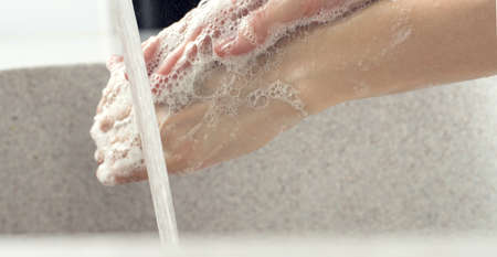 Washing of hands with soap under the crane with waterの写真素材