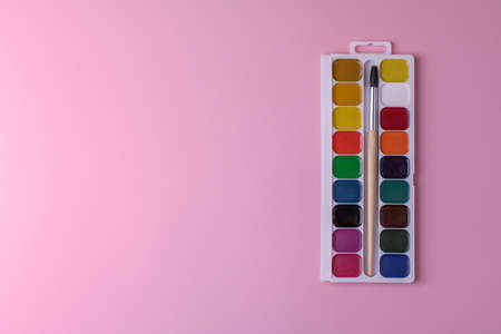 Rectangular box palette with honey colored watercolors and a brush on a pink background , top viewの写真素材