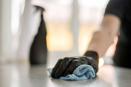 A hand in black gloves holds a microfiber cleaning cloth and a spray with sterilizing make disinfection for good hygieneの写真素材