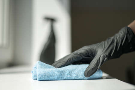A hand in black gloves holds a microfiber cleaning cloth and a spray with sterilizing make disinfection for good hygieneの写真素材