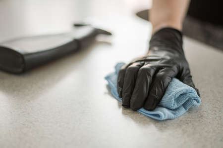 A hand in black gloves holds a microfiber cleaning cloth and a spray with sterilizing make disinfection for good hygieneの写真素材