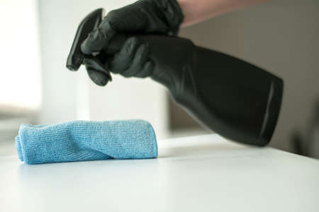 A hand in black gloves holds a microfiber cleaning cloth and a spray with sterilizing make disinfection for good hygieneの写真素材