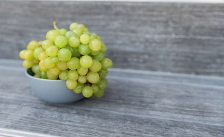 A bunch of ripe green grapes in a gray plat on a gray background.の写真素材