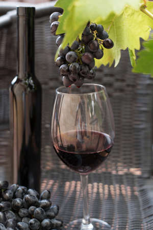 glass and bottle of dark red wine and grapes on a dark backgroundの写真素材