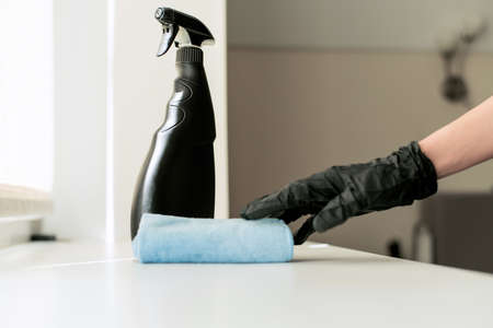 A hand in black gloves holds a microfiber cleaning cloth and a spray with sterilizing make disinfection for good hygieneの写真素材