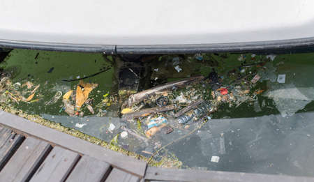 A disgusting pile of pollution floats in the sea under the boatの写真素材