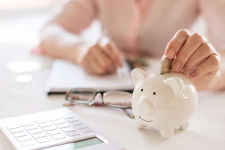 Old women's hands put money in the piggy Bank, the concept of retirement, savings.の写真素材