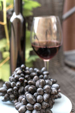 glass and bottle of dark red wine and grapes on a dark background.の写真素材