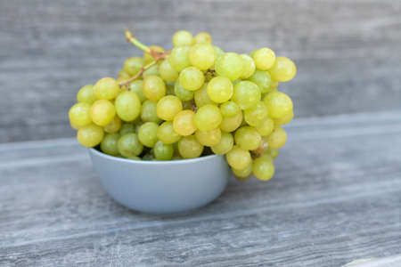 A bunch of ripe green grapes in a gray container on a gray backgroundの写真素材