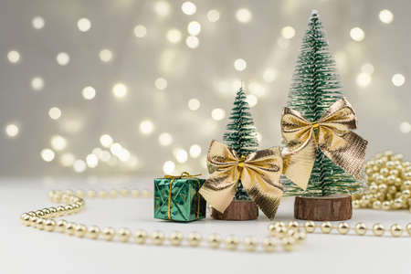 decorative Christmas trees decorated and gifts for the new year on the background of Golden bokeh lights, new year background, new year mood 2021.の写真素材