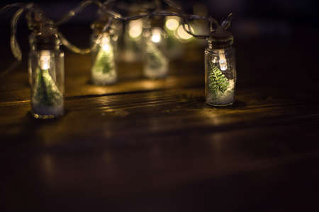Low key Image of christmas tree in mason jar with garland warm lights next to santa hatの写真素材
