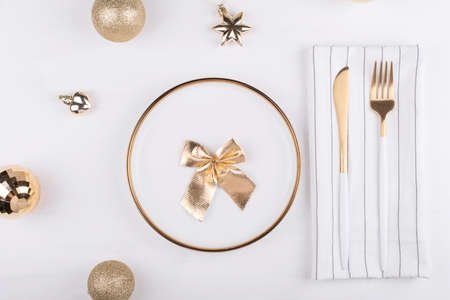 White plate with a gold border with Christmas decorations around it, New year's menu, festive table setting.の写真素材