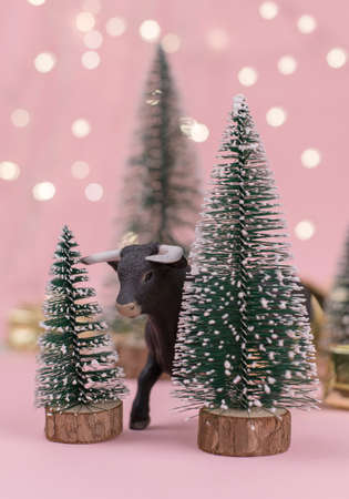 Decorative bull symbol of New Year on the pink background of Christmas tree and bokehの写真素材