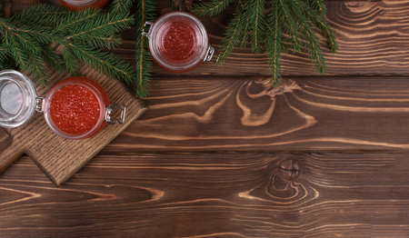Red caviar in a glass jar on a seasoned white wooden background with a Christmas tree. Copy Spaceの写真素材