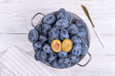 Lots of ripe juicy plums in a bowl on the tableの写真素材