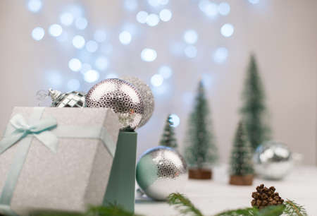 silver Christmas balls in a gift box on a background of Christmas trees and blue bokehの写真素材