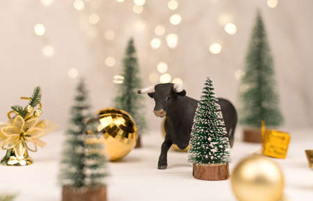 decorative bull, symbol of the New Year on the background of Christmas trees and Golden bokeh.の写真素材
