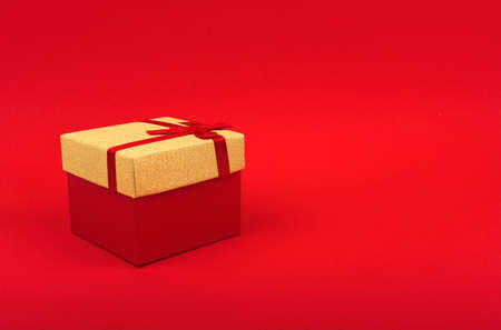 red square gift box with gold cover on red background, minimalism, new year gift.の写真素材