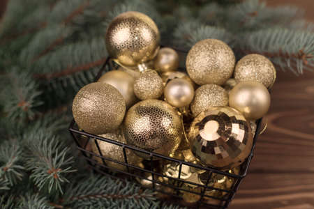 Stylish bucket of Christmas Golden toys on a wooden background and branches of Christmas trees.の写真素材
