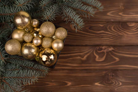 Stylish box of Christmas Golden toys on a wooden background and branches of Christmas trees. Copy spaceの写真素材
