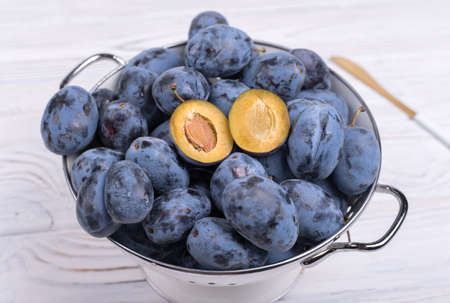 Lots of ripe juicy plums in a bowl on the table.の写真素材