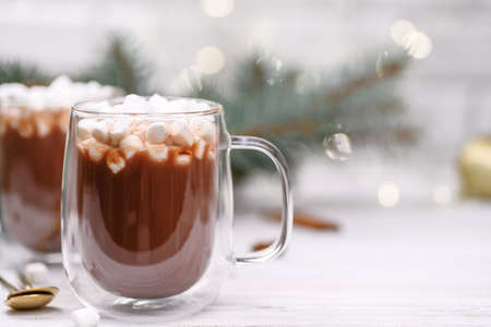 Glass cup of hot cocoa with christmas tree on the buckground of gold bokeh, New Year hot drink.の写真素材
