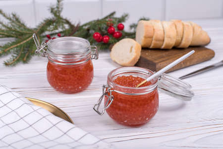 Red caviar in glass jar on aged white wooden background. Main dish New Year.の写真素材