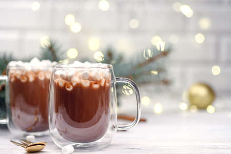 Glass cup of hot cocoa with christmas tree on the buckground of gold bokeh, New Year hot drink.の写真素材