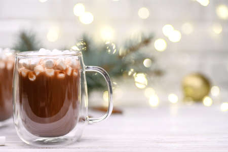Glass cup of hot cocoa with christmas tree on the buckground of gold bokeh, New Year hot drink.の写真素材
