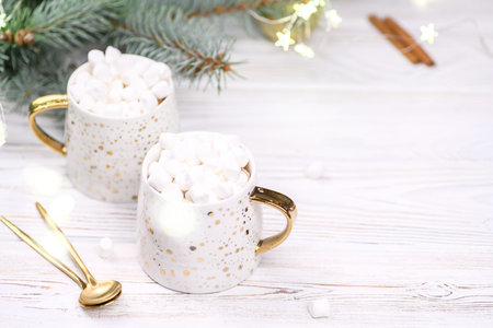 White cup of cappuccino or cocoa with christmas tree on the buckground of gold bokeh, New Year hot...