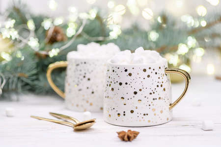 White cup of cappuccino or cocoa with christmas tree on the buckground of gold bokeh, New Year hot drink.の写真素材