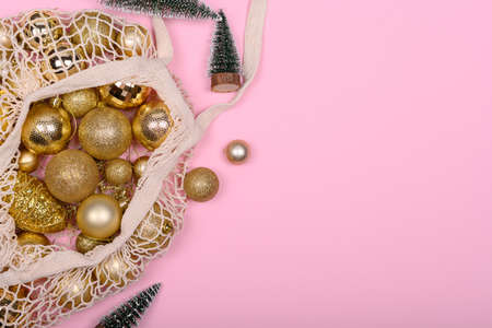 Eco-friendly bag with golden Christmas balls on a pink background, Zero Waist NY.の写真素材