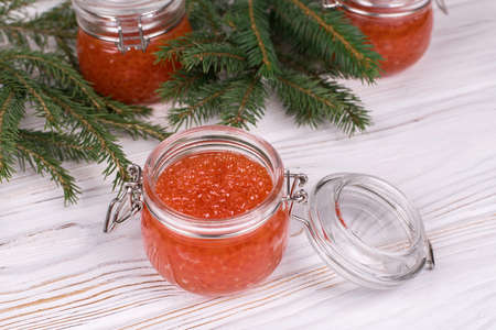 Red caviar in glass jar on aged white wooden background. Main dish New Year.の写真素材