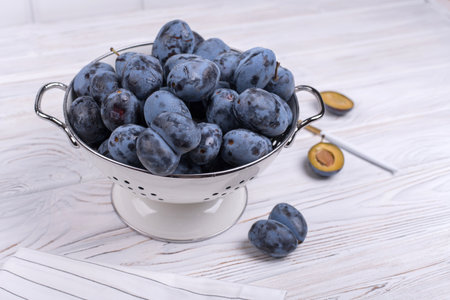 Lots of ripe juicy plums in a bowl on the table.の写真素材