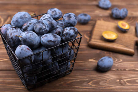 Lots of ripe juicy plums in a bowl on the woodentable.の写真素材