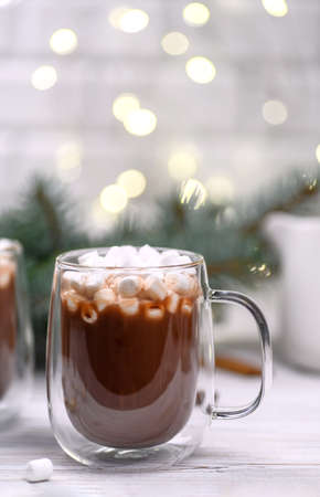 Glass cup of hot cocoa with christmas tree on the buckground of gold bokeh, New Year hot drink.の写真素材