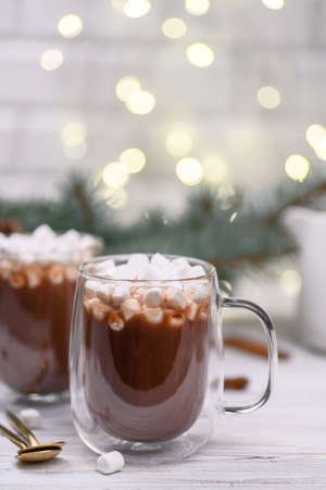 Glass cup of hot cocoa with christmas tree on the buckground of gold bokeh, New Year hot drink.の写真素材