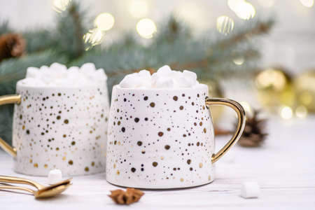 White cup of cappuccino or cocoa with christmas tree on the buckground of gold bokeh, New Year hot drink.の写真素材