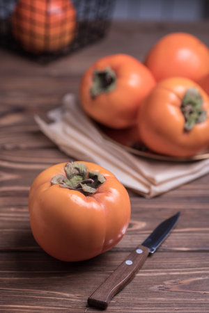 Delicious fresh orange persimmon fruit on wooden table with knifeの写真素材