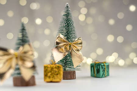 decorative Christmas trees decorated and gifts for the new year on the background of Golden bokeh lights, new year background, new year mood 2021.の写真素材